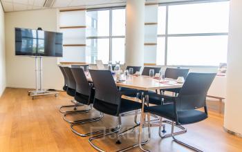 A bright conference room at Radarweg 29, Amsterdam Sloterdijk, available for office space rental with a large table, chairs, and a screen.