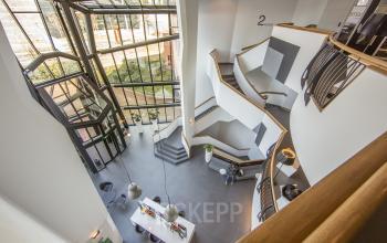 Modern office space rental at Kingsfordweg 151, Amsterdam Sloterdijk, featuring an elegant staircase and a bright, airy atrium.
