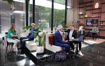 Modern office space at Teleportboulevard 110, Amsterdam Sloterdijk, featuring business professionals in meetings and discussions. Ideal office space rental with stylish décor and natural light.