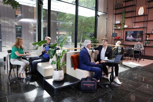 Professionals engaging in business activities in a modern office lounge at Teleportboulevard 110, offering a comfortable office space rental in Amsterdam Sloterdijk.