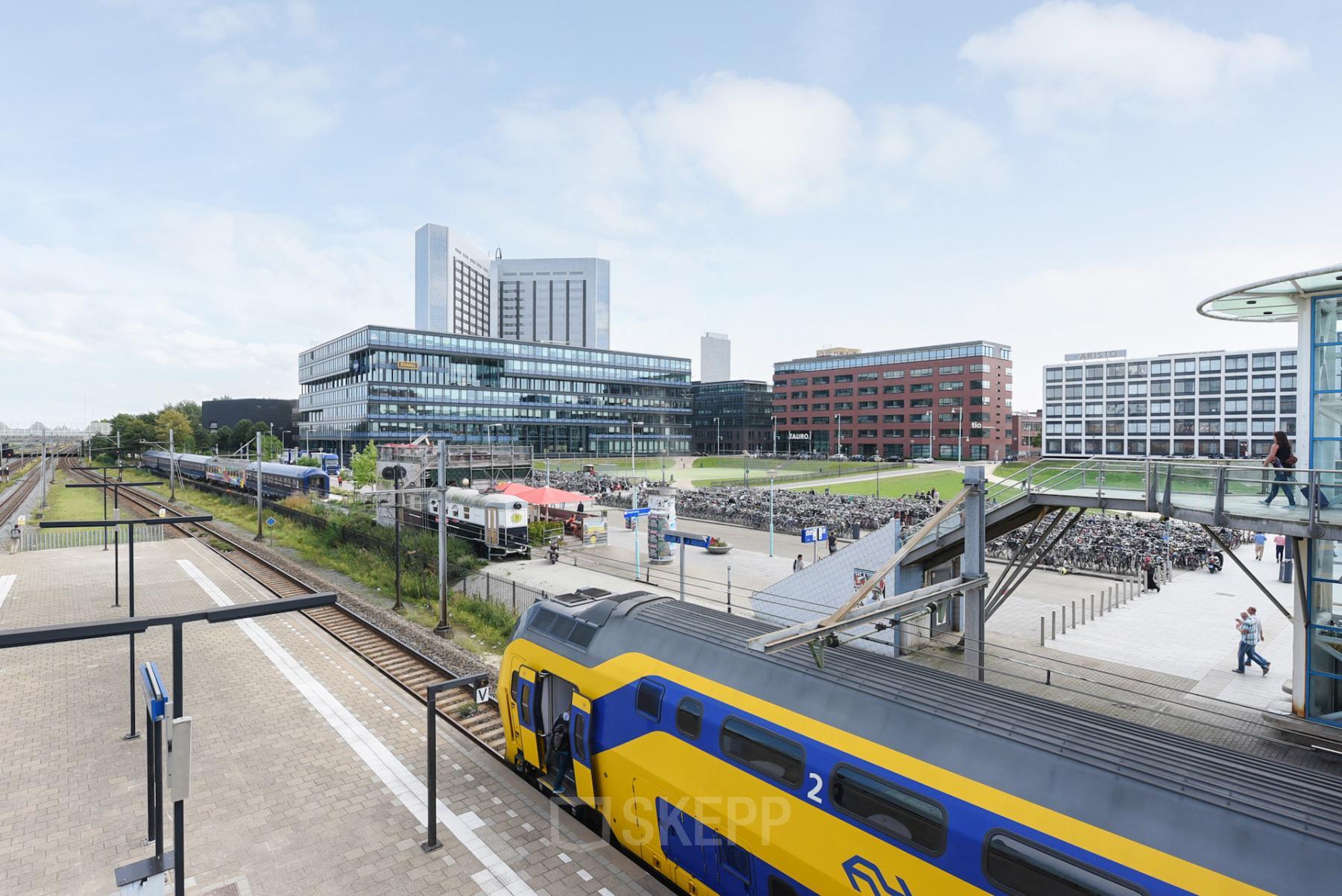 Modern office space rental at Teleportboulevard 110, Amsterdam Sloterdijk with a vibrant outdoor view showcasing commuting facilities.