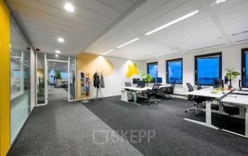 Spacious office space rental at Radarweg 501, Amsterdam Sloterdijk, featuring modern workstations, bright yellow accents, and large windows overlooking the city. Ideal office to rent with natural lighting.