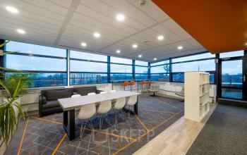 Modern office space at Radarweg 501, Amsterdam Sloterdijk, featuring a large table with chairs, cozy seating area, and panoramic windows offering great views, ideal for office space rental.