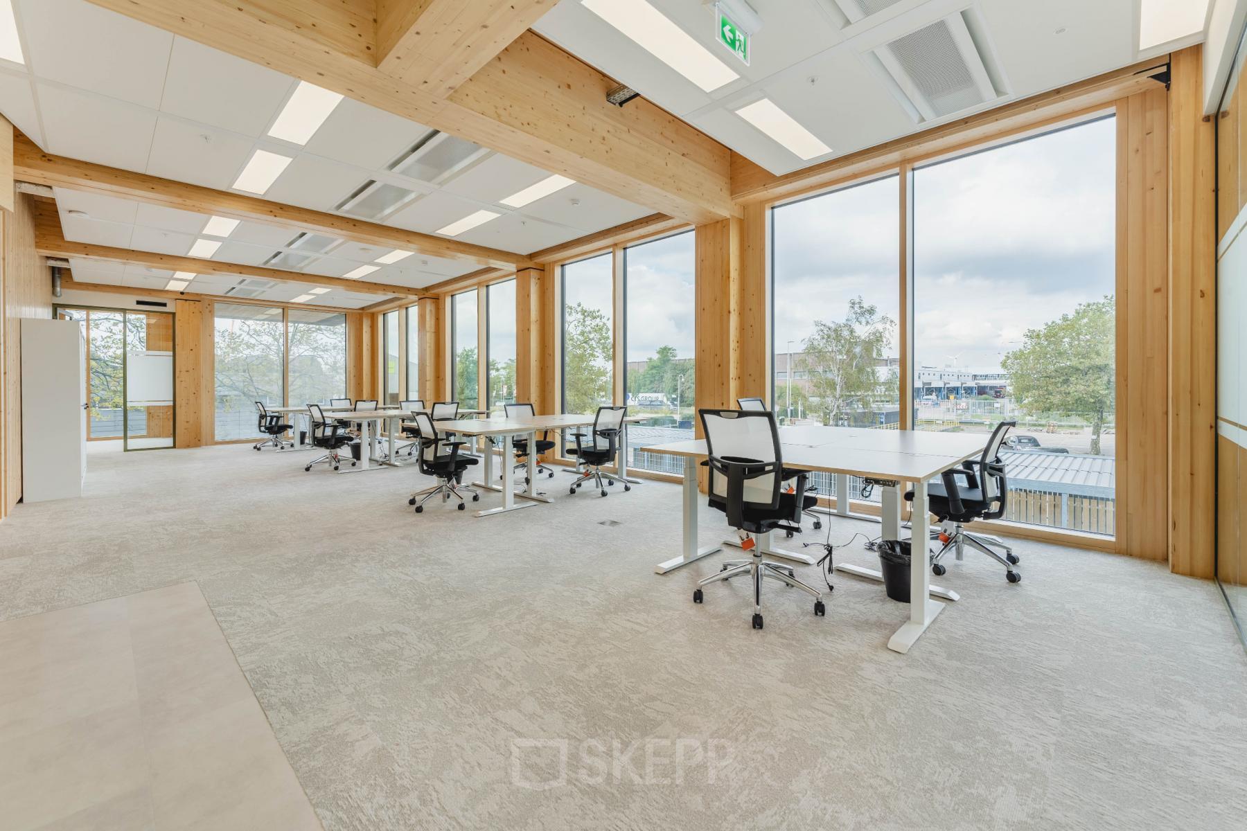 Bright, modern office space with large windows and multiple workstations at Basisweg 32 in Amsterdam Sloterdijk, suitable for office space rental.