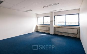 Vacant office space with blue carpet and large windows at Kabelweg 24, Amsterdam Sloterdijk, available for rent.
