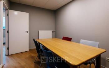 Compact conference room with a wooden table and colorful chairs, located at Kabelweg 24 in Amsterdam Sloterdijk, suitable for office space rental.