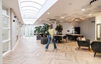 Modern office space rental in Amsterdam Sloterdijk at Arlandaweg 92, featuring stylish seating areas, plants, and people engaged in business activities.