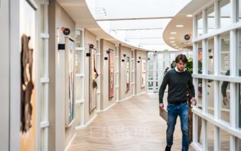 Modern corridor in office building at Arlandaweg 92, Amsterdam Sloterdijk, with a person walking and glass-paneled rooms on either side.