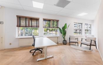 Bright office space at Arlandaweg 92 in Amsterdam Sloterdijk, featuring a desk and chairs with large windows providing natural light, ideal for office space rental opportunities.