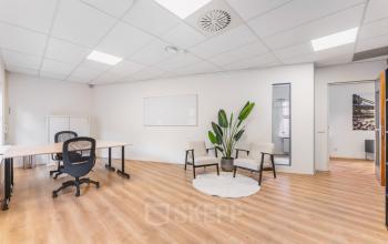 Bright office space with wooden flooring, two modern chairs, a desk with an office chair, and a potted plant. Ideal for office space rental in Amsterdam Sloterdijk.