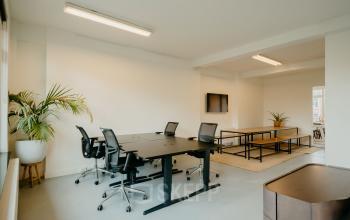 Bright workspace at Overtoom 141, Amsterdam West with modern furnishings, including ergonomic chairs and desks, ideal for office space rental. Features natural light and minimal decor with greenery.