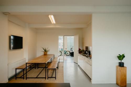 Bright office interior at Overtoom 141, Amsterdam West, featuring a modern kitchen area with a long wooden table, benches, and indoor plants, ideal for office space rental.