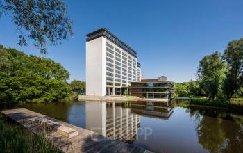 Exterior view of an office building at Nachtwachtlaan 20, Amsterdam West, ideal for office space rental, with a pond and surrounding greenery.