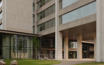 Exterior view of an office building at Nachtwachtlaan 20, Amsterdam West. The entrance features large glass windows and a modern facade, ideal for office space rental.