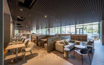 Spacious, well-lit lounge area for office space rental at Nachtwachtlaan 20, Amsterdam West, featuring comfortable seating and a modern design.