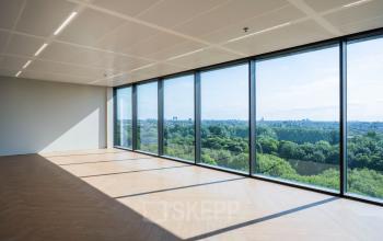 Spacious office area with large windows offering a panoramic view of greenery in Amsterdam West, perfect for office space rental.