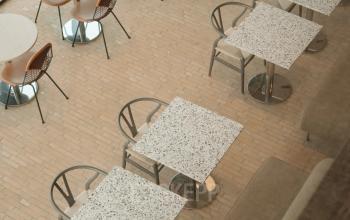 Modern office space rental in Amsterdam West features an airy area with several tables and chairs, ideal for meetings or collaboration.