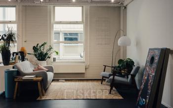 Cozy lounge area at Rigakade 10 in Amsterdam West, featuring comfortable seating, plants, and natural light, ideal for casual meetings or breaks. Consider this layout for office space rental.
