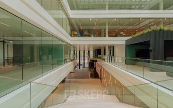 Spacious interior with modern glass architecture at Kon. Wilhelminaplein 4, Amsterdam West, perfect for rent office space. Bright and open with sleek design, offering potential for versatile office space rental.