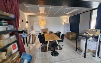 Interior of office space at Gyroscoopweg 23-25 in Amsterdam Westpoort, featuring a large wooden table, chairs, lighting fixtures, and various office materials and boxes.