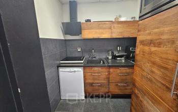 Modern pantry in the office located at Gyroscoopweg 23-25, Amsterdam Westpoort, with wooden cabinets, a dishwasher, microwave, and induction stove.