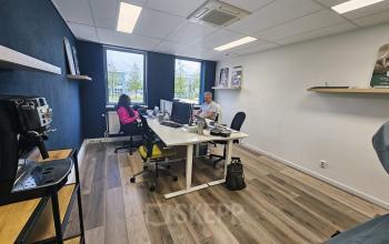 Office space at Gyroscoopweg 23-25, Amsterdam Westpoort, featuring a modern workspace with desks, chairs, and people working on computers.