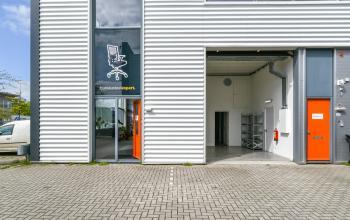 Exterior view of an office building at Poortland 242, Amsterdam Westpoort, featuring large windows and orange doors, perfect for office space rental.