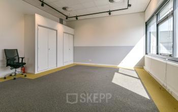 Bright office space with carpeted flooring, large windows, and built-in storage at Poortland 242, available for office space rental in Amsterdam Westpoort.