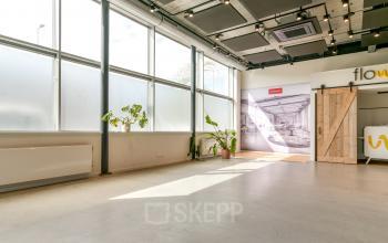Spacious office area with large windows and potted plants at Poortland 242, Amsterdam Westpoort. Ideal for office space rental, offering ample natural light and an open layout.