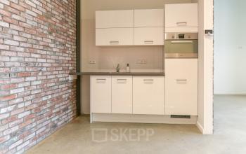 Modern office pantry at Poortland 242 in Amsterdam Westpoort featuring brick walls, sleek cabinets, and built-in appliances. Ideal for office space rental, enhancing your workspace with functionality and style.