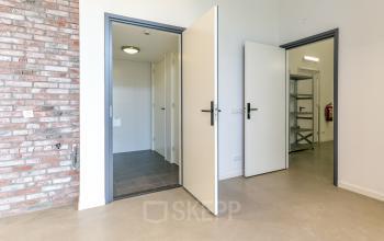 Interior view of an office space at Poortland 242, Amsterdam Westpoort, featuring open doors to storage areas with brick wall accents, ideal for office space rental.