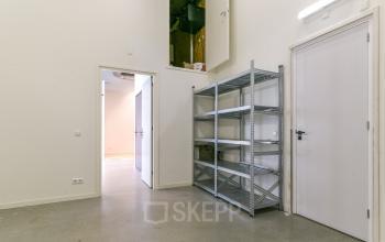 Interior of an office space with grey flooring and metallic shelving, located at Poortland 242, Amsterdam Westpoort. This area may be suitable for office space rental.