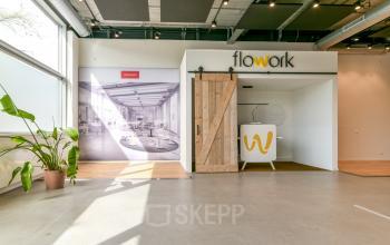 Office space rental at Poortland 242 in Amsterdam Westpoort features a modern, inviting entrance with a rustic sliding barn door and large window letting in natural light.