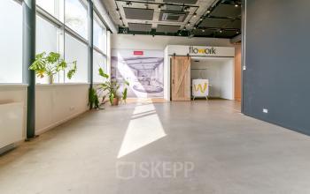 Spacious, well-lit office interior at Poortland 242, Amsterdam Westpoort, showcasing polished concrete floors and large windows for natural light, ideal for diverse workspace configurations. Office space rental options available.
