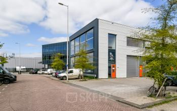 Modern office building for office space rental at Poortland 242, Amsterdam Westpoort, featuring sleek architecture with large windows and surrounding parking area.