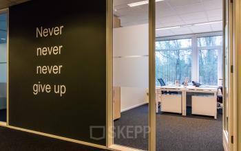 Office space to rent at Hullenbergweg 278, Amsterdam South East, featuring a motivational wall and a view into a bright, furnished workspace with desks and chairs.