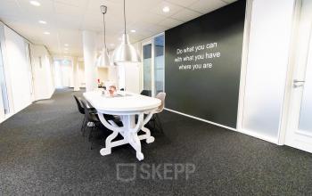 Bright office space at Hullenbergweg 278 in Amsterdam South East, featuring a modern meeting table and motivational wall art, ideal for rent office space seekers.