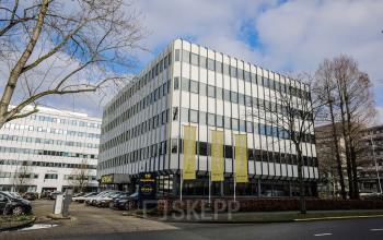 Modern exterior of office space rental at Hogehilweg 19 in Amsterdam South East with parked cars and trees.