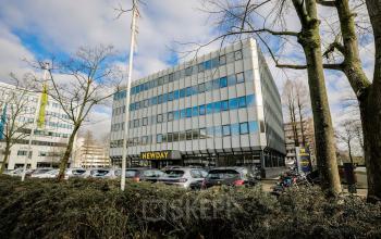 Modern office space rental at Hogehilweg 19, featuring a sleek facade with ample parking in Amsterdam South East.