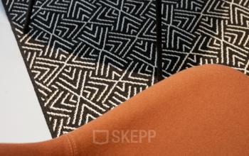 Close-up of a stylish chair with a geometric patterned carpet, a detail that adds a touch of sophistication to the office space rental at Hogehilweg 19, Amsterdam South East.