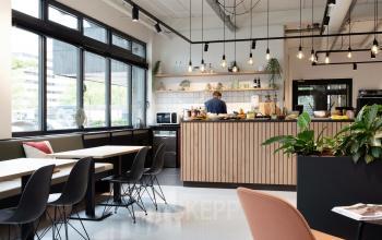 Modern office pantry at Hogehilweg 19, Amsterdam Southeast, featuring ample natural light, seating, and contemporary fixtures.