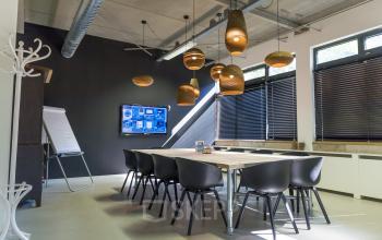 Sleek and modern office space rental at Hogehilweg 19, Amsterdam South East, featuring a conference table, designer lighting, and tech-equipped presentation area.