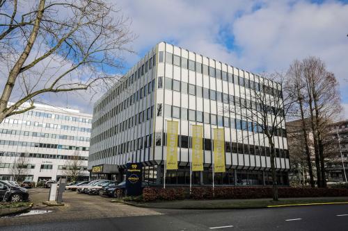 Modern exterior of office space rental at Hogehilweg 19 in Amsterdam South East with parked cars and trees.