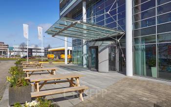 Exterior view of modern office building at Laarderhoogtweg with outdoor seating in Amsterdam South East, ideal for office space rental.
