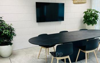 Modern office space at Laarderhoogtweg 7-19, Amsterdam South East featuring a sleek conference room with a central table, chairs, and a large wall-mounted screen, ideal for meetings.