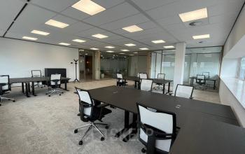 Interior view shows a furnished workspace at Laarderhoogtweg 7-19 in Amsterdam South East, ideal for office space rental with multiple desks and chairs under bright lighting.