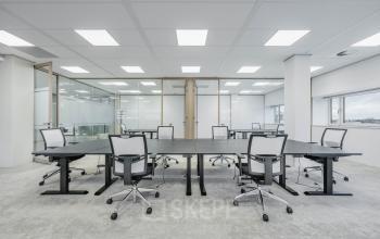 Spacious office interior in Amsterdam South East with modern furnishings and multiple desks, ideal for office space rental.