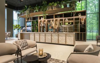 Modern, furnished office lounge at De Entree 201, Amsterdam South East with stylish seating and greenery. Ideal for office space rental.