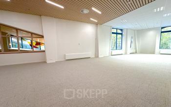 Spacious, well-lit office space available for rent at Bijlmerplein 888, Amsterdam South East, featuring large windows and modern ceiling lights.