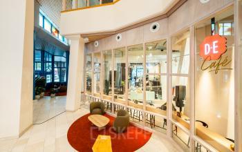 Inviting and modern lobby area with a view into an open office space. Comfortable seating and glass walls enhance the sense of openness, ideal for a collaborative office space rental.